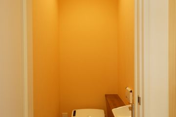 イエローの壁紙で明るい空間のトイレ